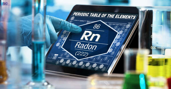 A scientist wearing gloves points to a digital tablet showing Radon (Rn) on the Periodic Table of the Elements.